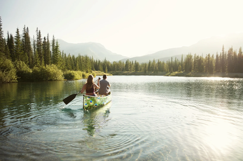 Couple rowing a canoe across a calm lake