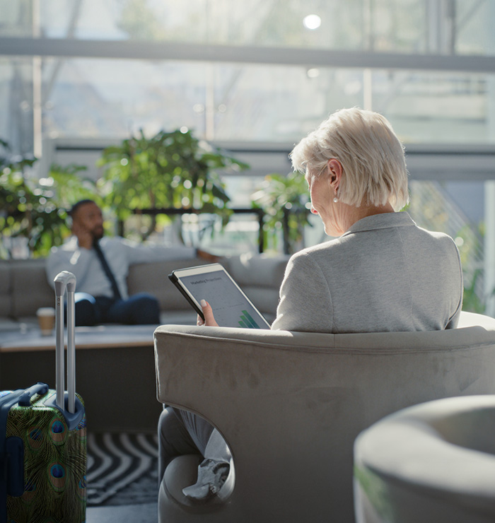 Business women sat in armchair reading report on tablet