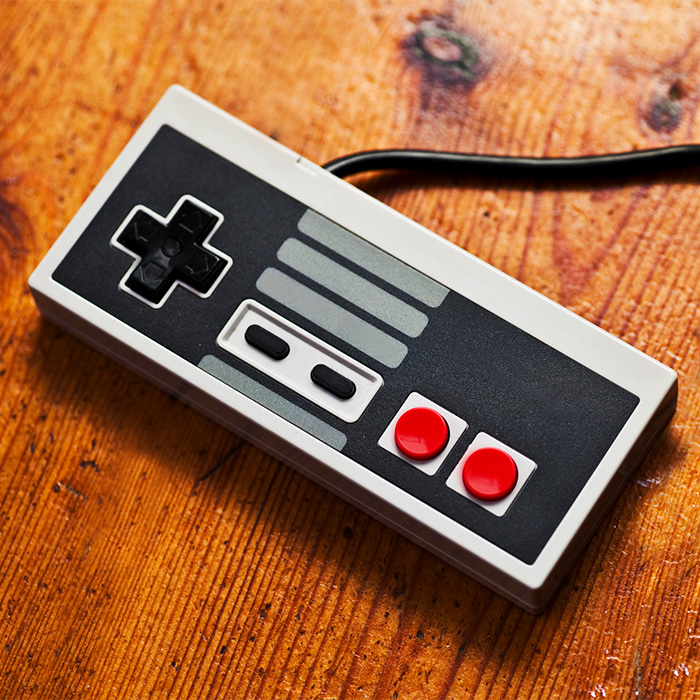 Close up of a retro game console controller on a wooden surface.