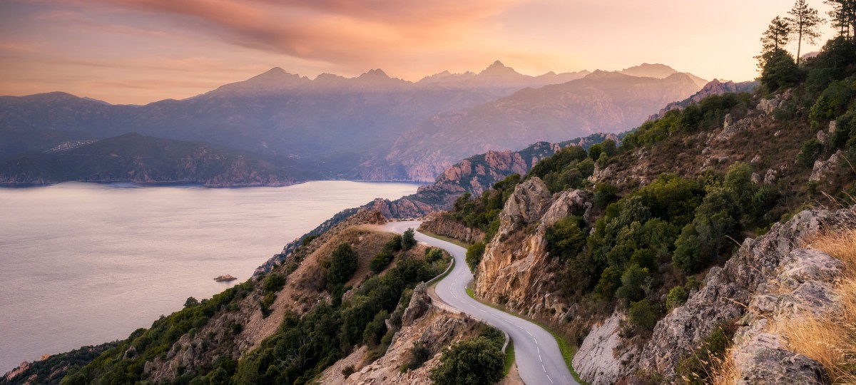 Winding road through cliffs at sunset