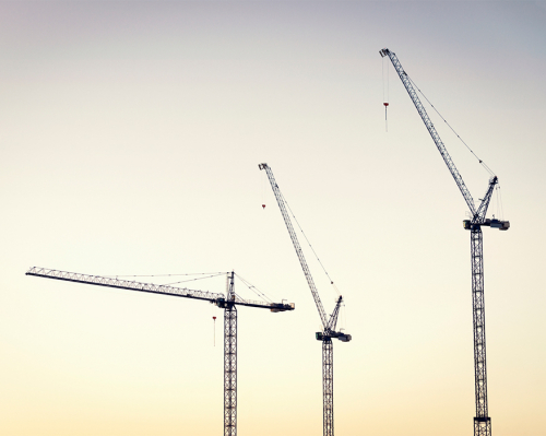 Image of three cranes silhouetted against the sky.