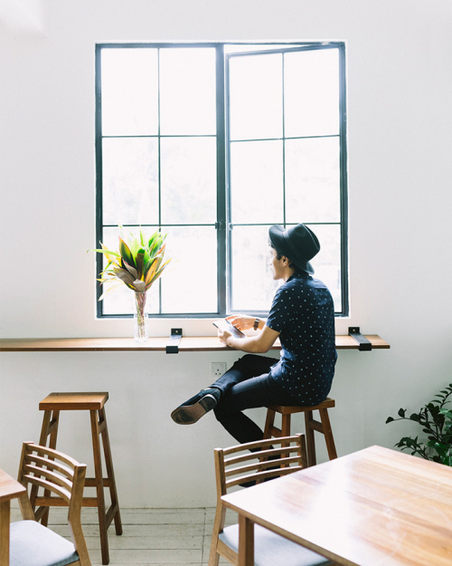 Man using tablet sat by cafe window