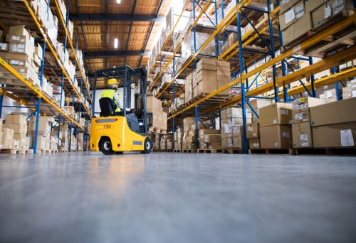 Man driving forklift truck in warehouse full of boxes