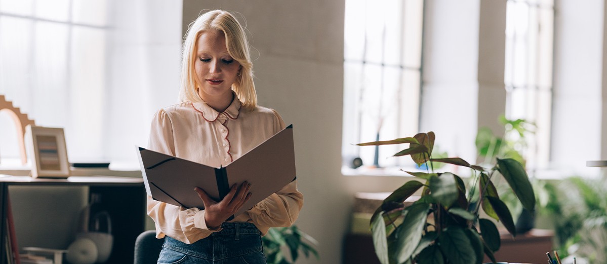 Businesswoman Standing at the Office and Reading a Report 