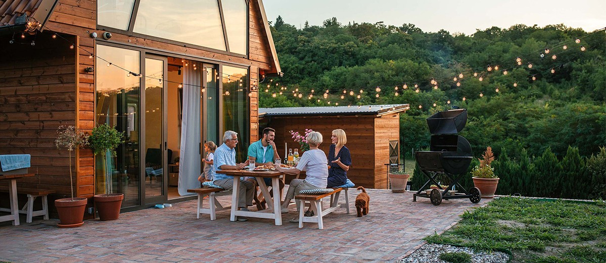 Family seated having barbecue in garden of modern house