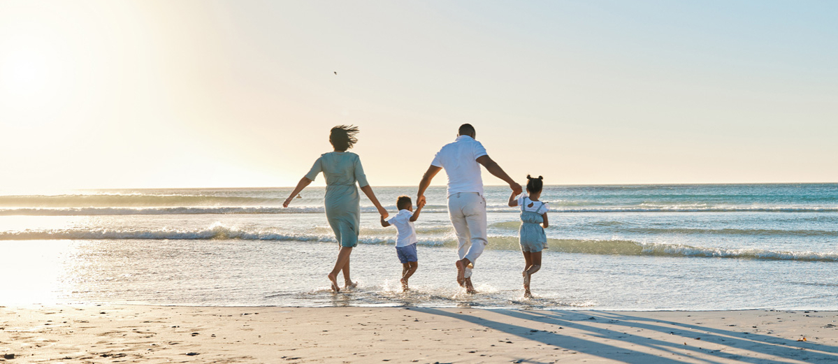 Rearview shot of a happy family walking towards the sea