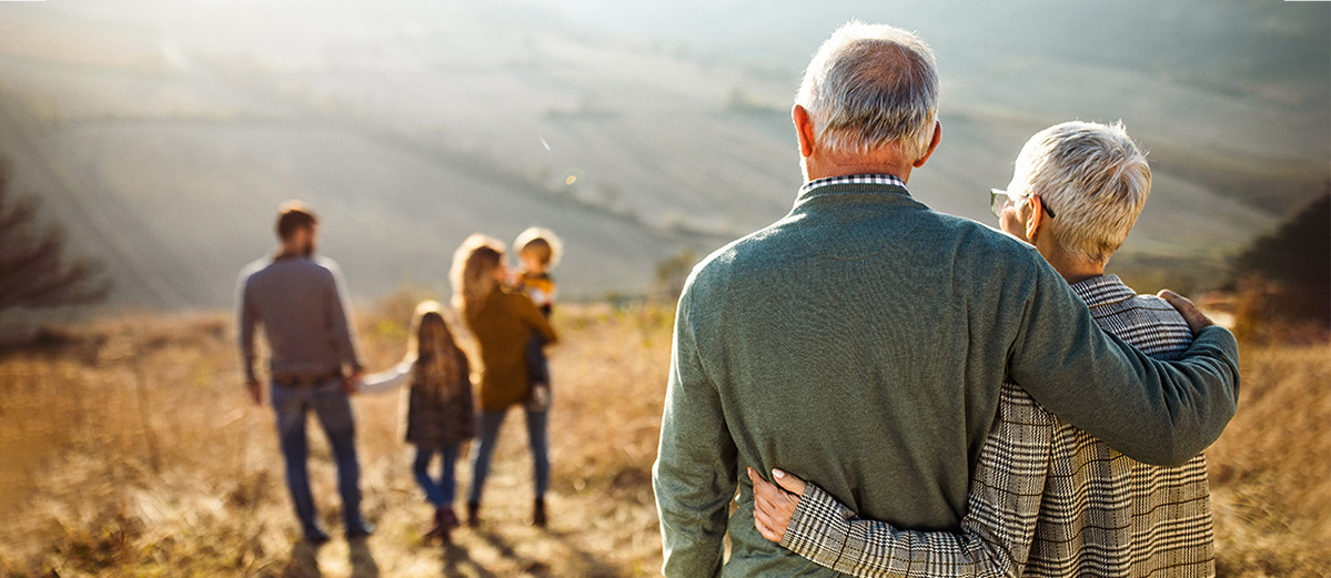 Senior couple watching their family on a countryside walk