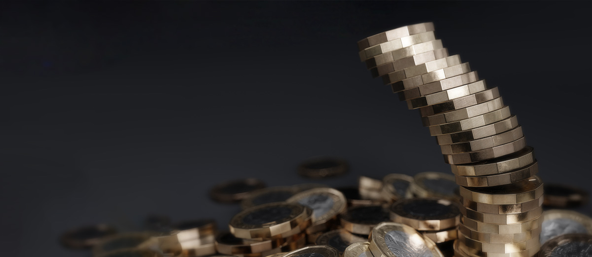A stack of pound coins toppling over on a dark grey background