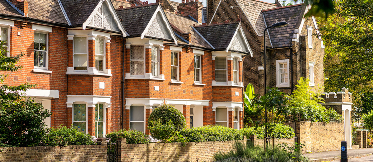 A row of terraced houses, with peacock feather patterned blinds in a window.