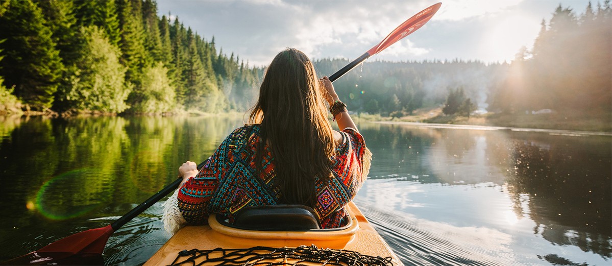 Woman kayaking along river surrounded by nature