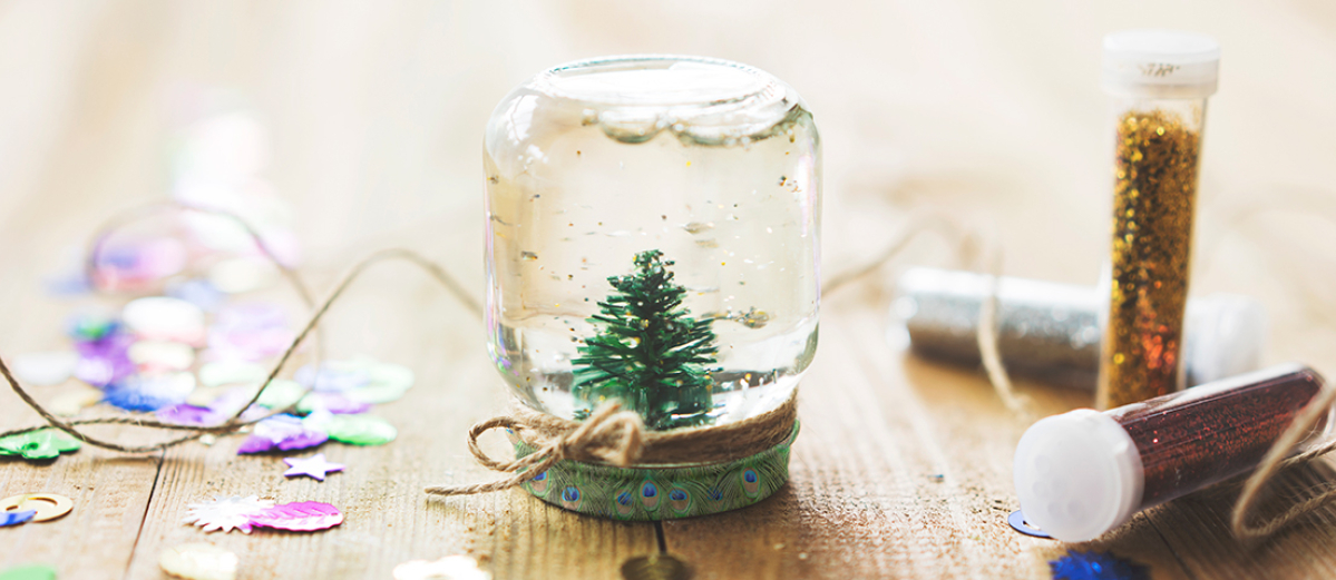 Close up of a small jar with a christmas tree in, along with some craft supplies.