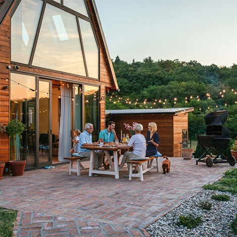 Family seated having barbecue in garden of modern house