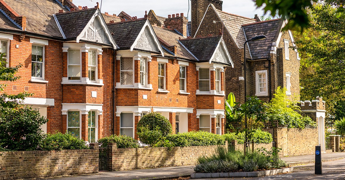 A row of terraced houses, with peacock feather patterned blinds in a window.