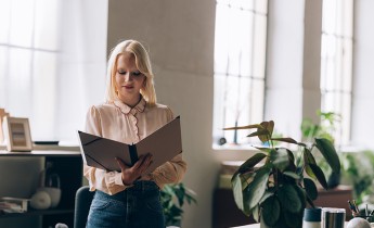 Businesswoman Standing at the Office and Reading a Report 