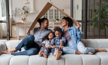 African family sit on couch under cardboard roof