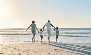 Rearview shot of a happy family walking towards the sea