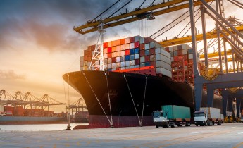 Ship carrying shipping containers in dockyard