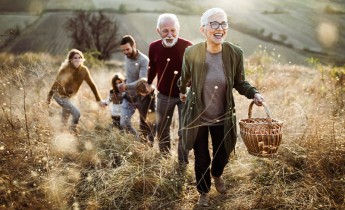 Happy senior woman leading her family to perfect picnic place on the hill