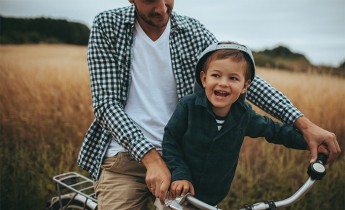 Little boy and his father riding a bicycle outdoors.