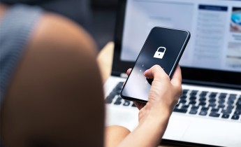 View over a woman's shoulder of her entering a password into a locked smartphone