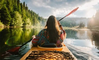 Woman kayaking along river surrounded by nature