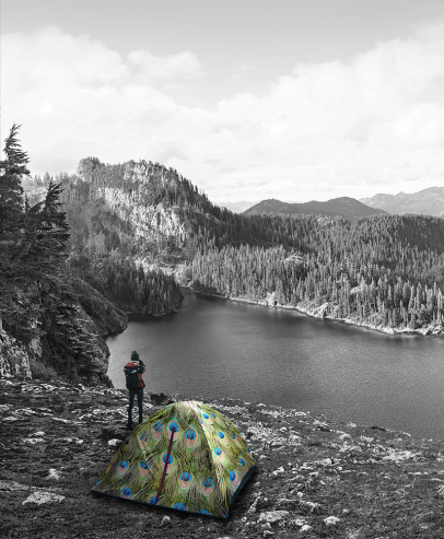 Man with tent on a hill in front of lake