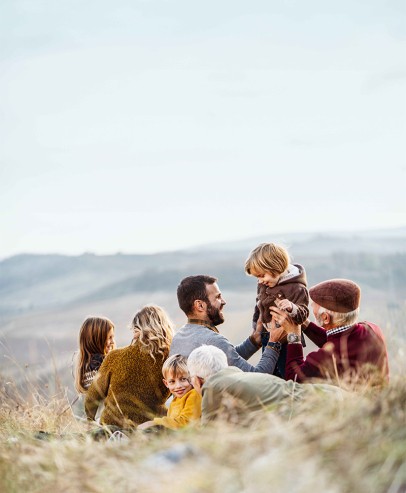 Multi-generational family seated together in grassy field
