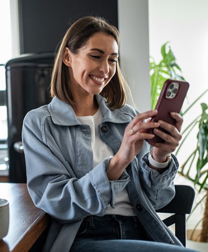  Young woman using smartphone and smiling in modern kitchen