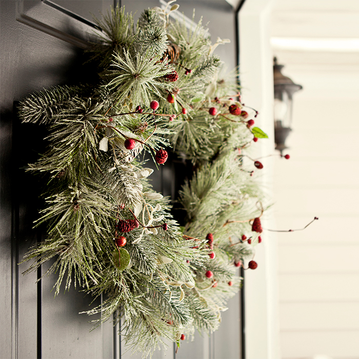 A Christmas wreath with red berries hanging on a front door.